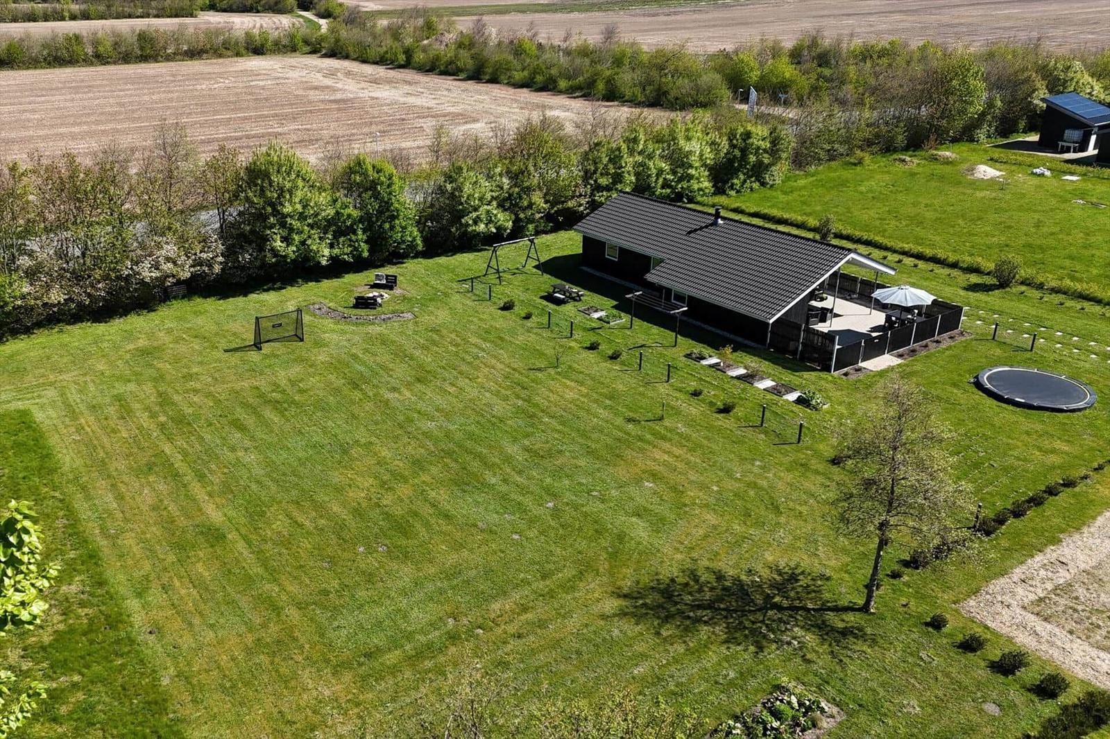 Haus mit großem Garten, Spielplatz, Trampolin und Terrasse mit Sonnenschirm.