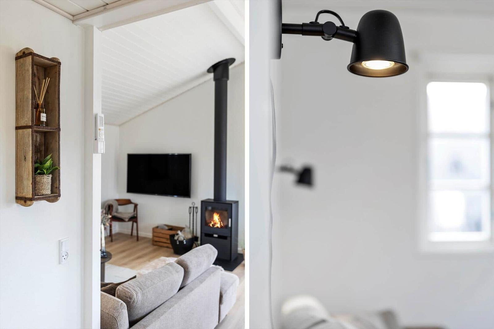 Wohnzimmer mit Kamin und Fernseher. Wandlampe und Holzregal an der Wand.