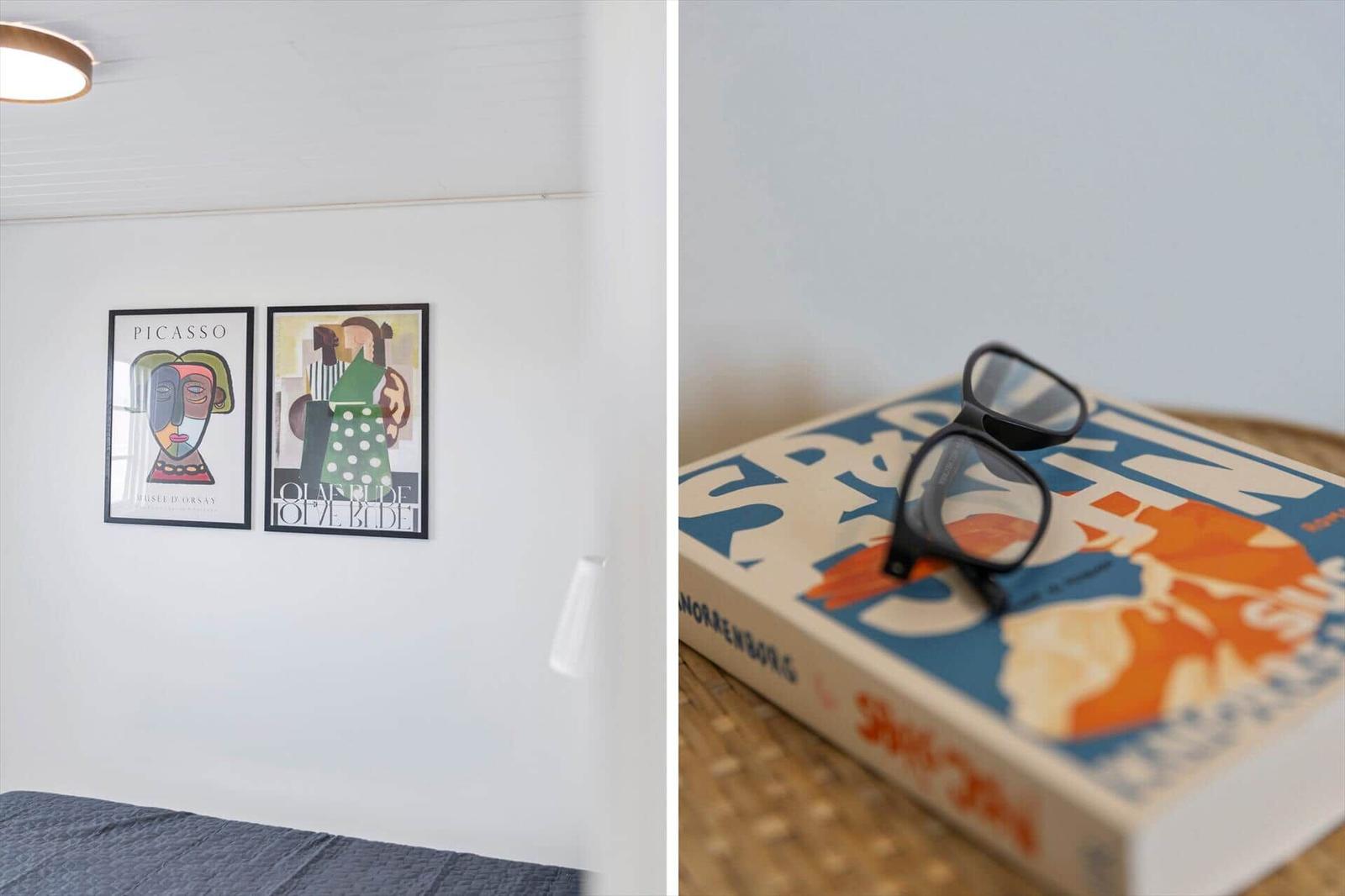 Zwei Bilder an der Wand und eine Brille auf einem Buch.