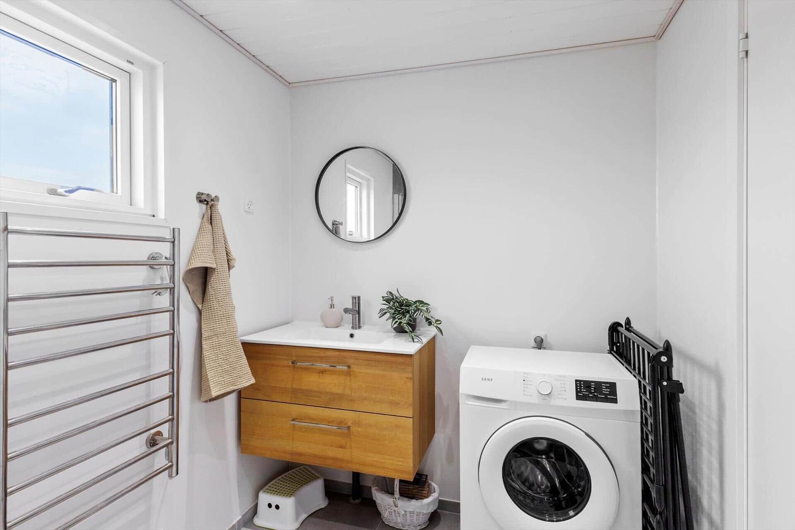 Badezimmer mit Waschmaschine, Spiegelschrank und Heizung.