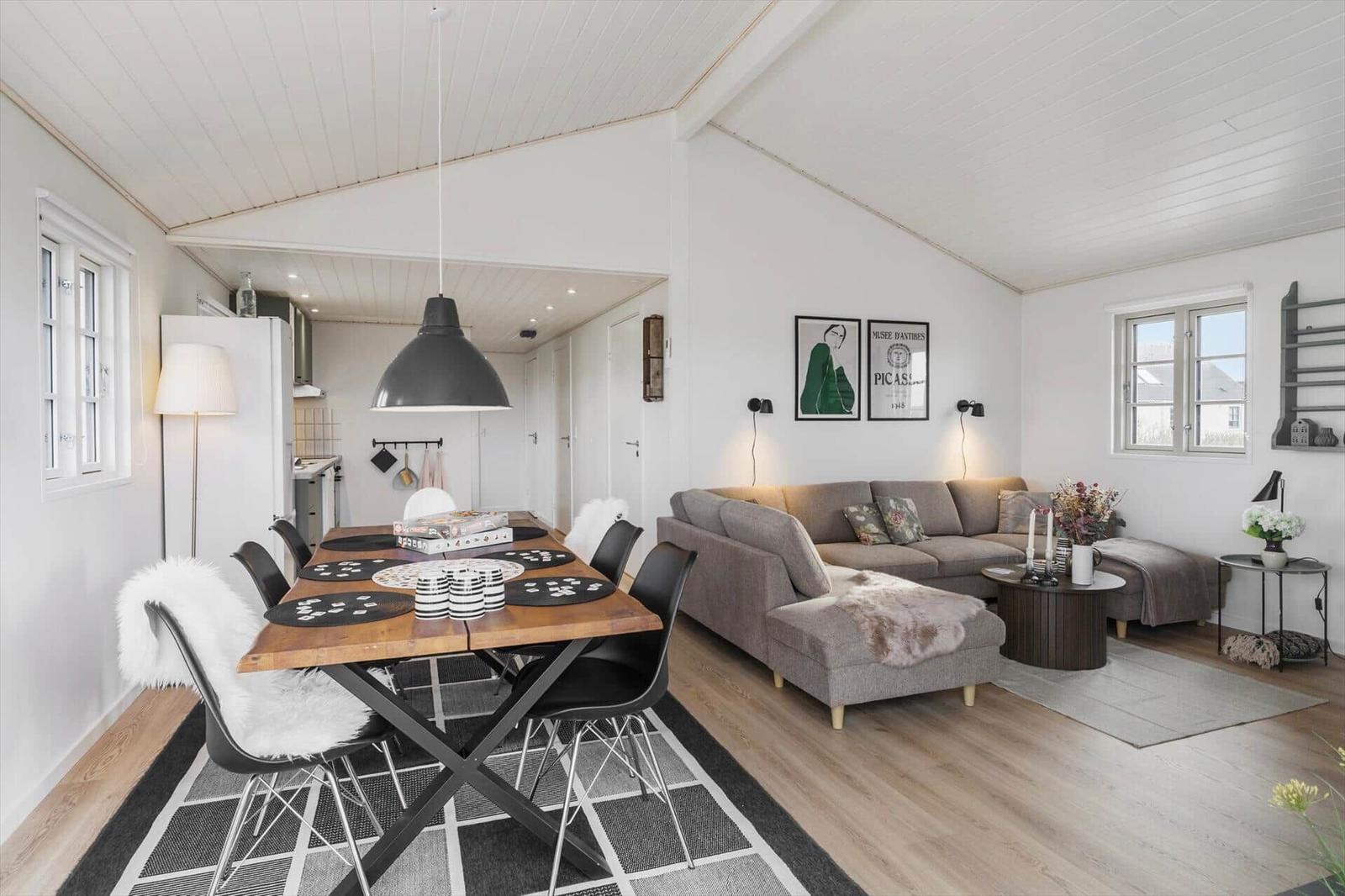 Wohn- und Essbereich mit Sofa, Esstisch und Küchenbereich im Hintergrund.