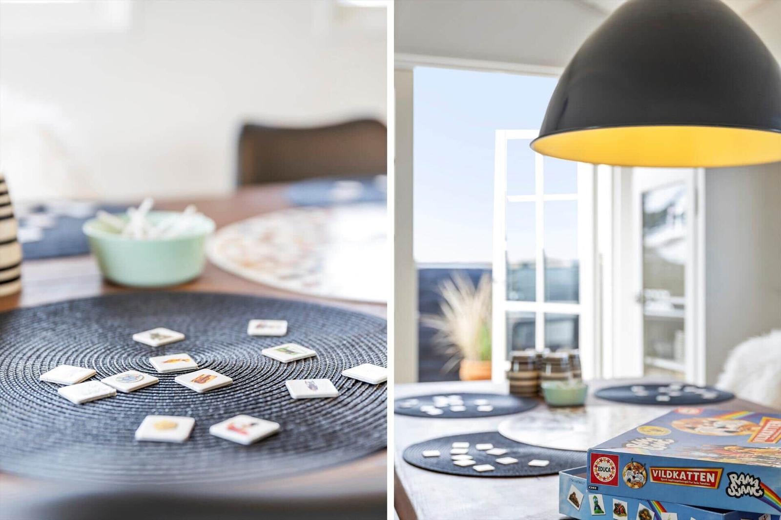 Tisch mit Spielkarten und Spielboxen, schwarze Lampe, Fenster zur Terrasse