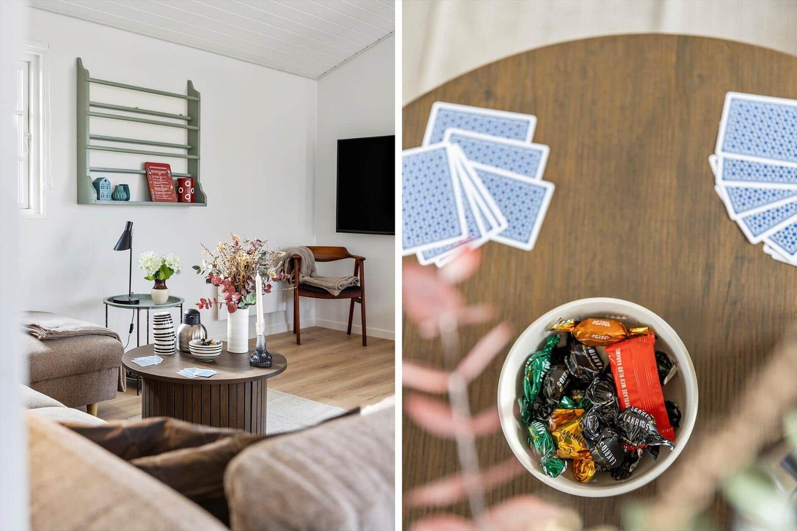 Wohnzimmer mit Couch, Tisch und Fernseher. Tisch mit Karten und Süßigkeiten.