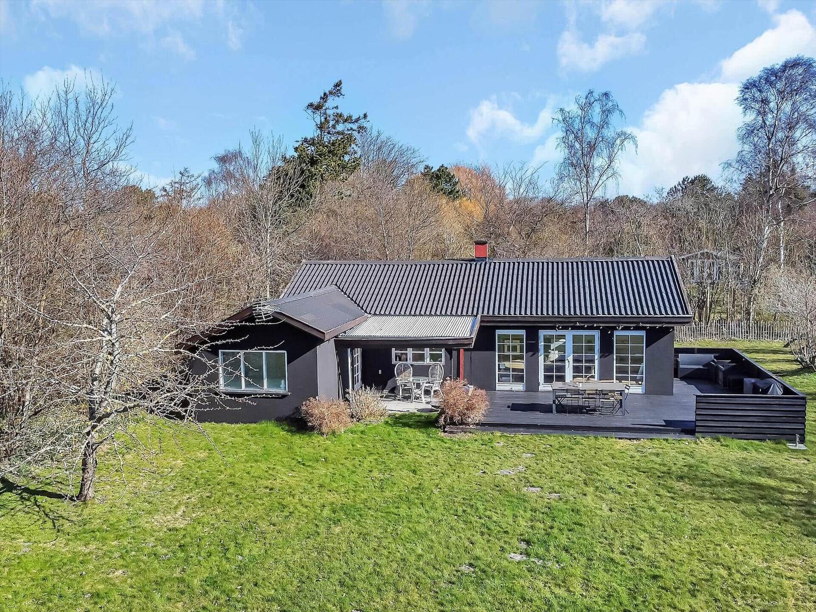 Moderne Villa mit Terrasse, Garten und Waldblick. Holzterrasse mit Sitzmöbeln.