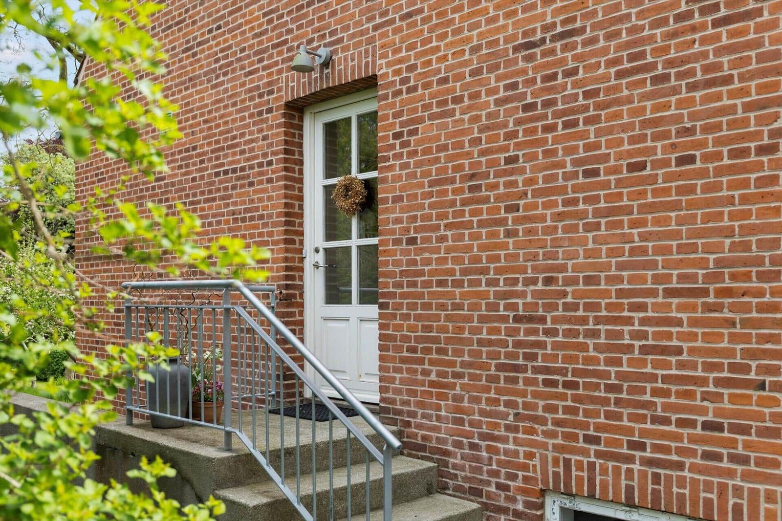 Red brick building with white door and steps to entrance.