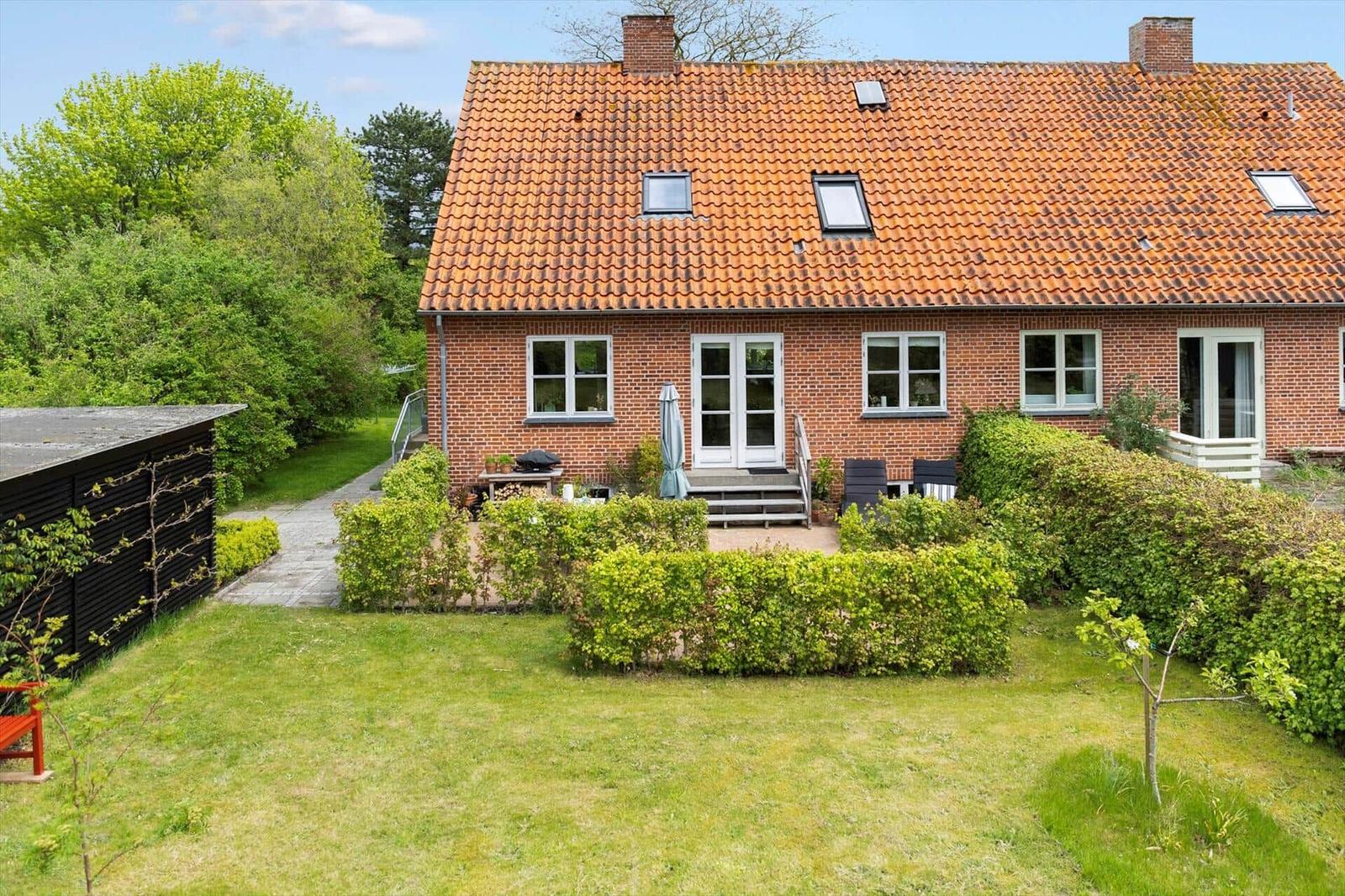 Red brick house with garden, terrace, and skylights.