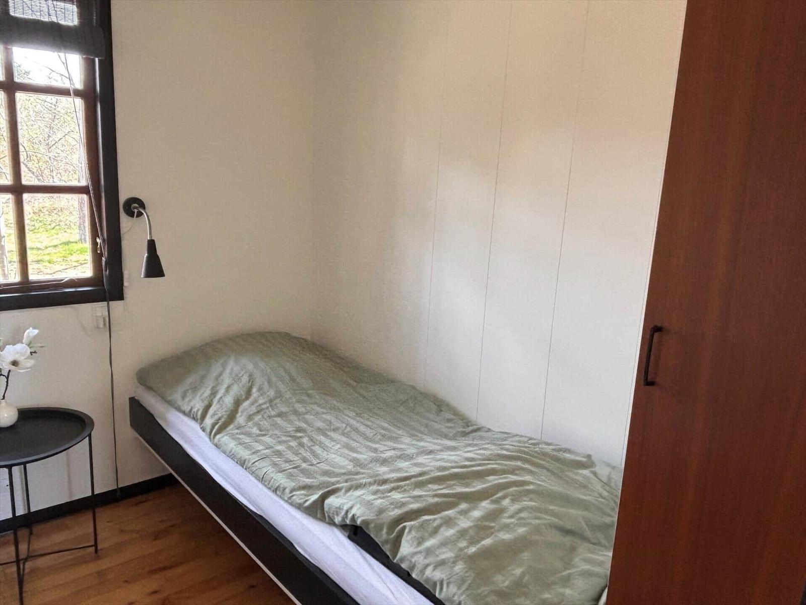 Schlafzimmer mit Einzelbett, Fenster und Kleiderschrank.