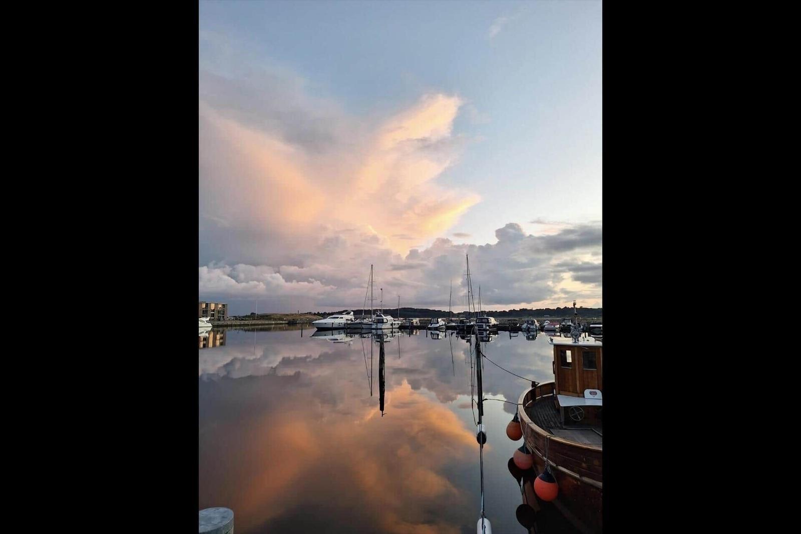 Sunset over harbor with boats and reflection in the water