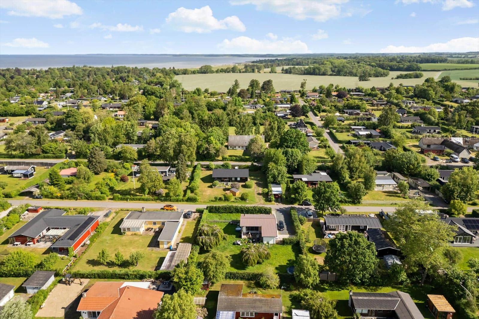 Aerial view of a residential area with houses, green spaces, and water in the distance