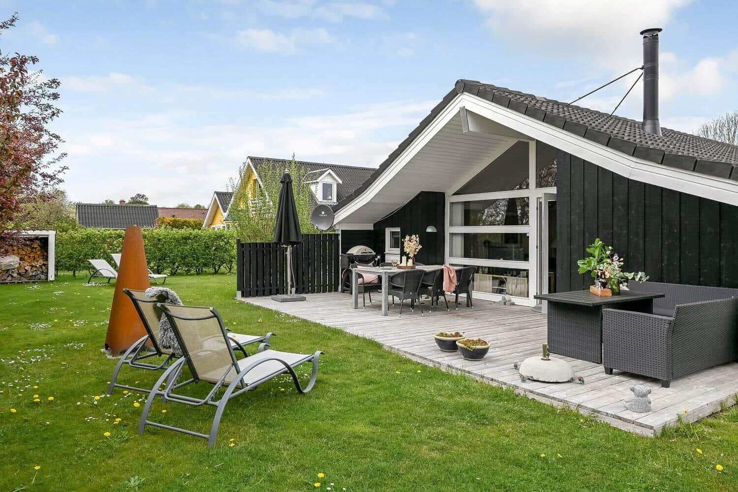 Haus mit Terrasse, Garten und Liegestühlen. Grill und Sitzgruppe vorhanden.