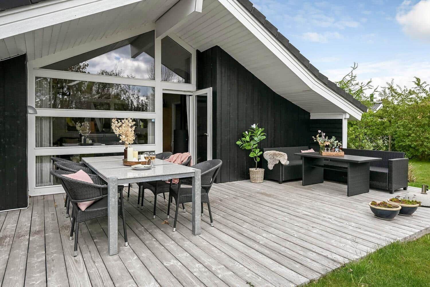 Terrasse mit Essbereich und Sitzgruppe, Holzdecke, Pflanzen und Blick auf Garten.