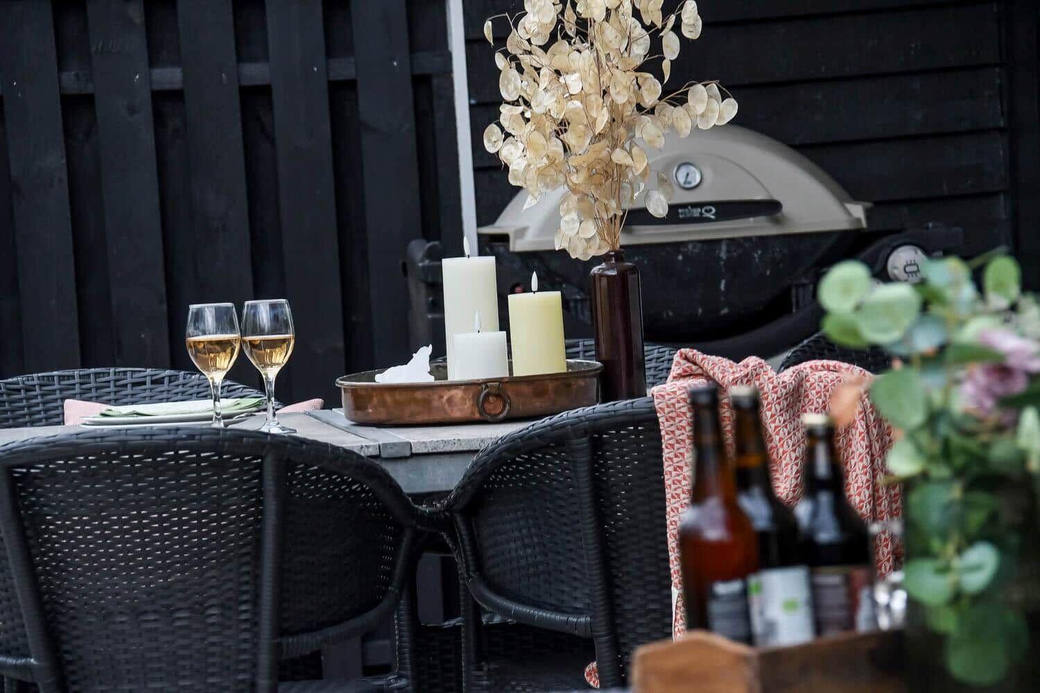 Außenbereich mit Tisch, Stühlen, Grill und dekorativen Elementen.