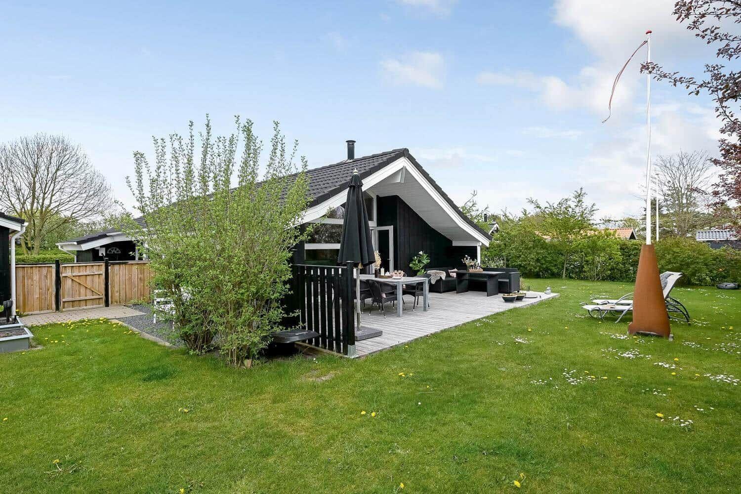 Schwarzes Haus mit Terrasse, Garten und Liegestühlen. Grillmöglichkeit vorhanden.