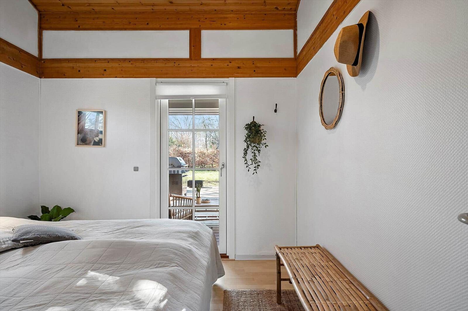 Schlafzimmer mit Bett, Tür zum Balkon und Wanddekoration.
