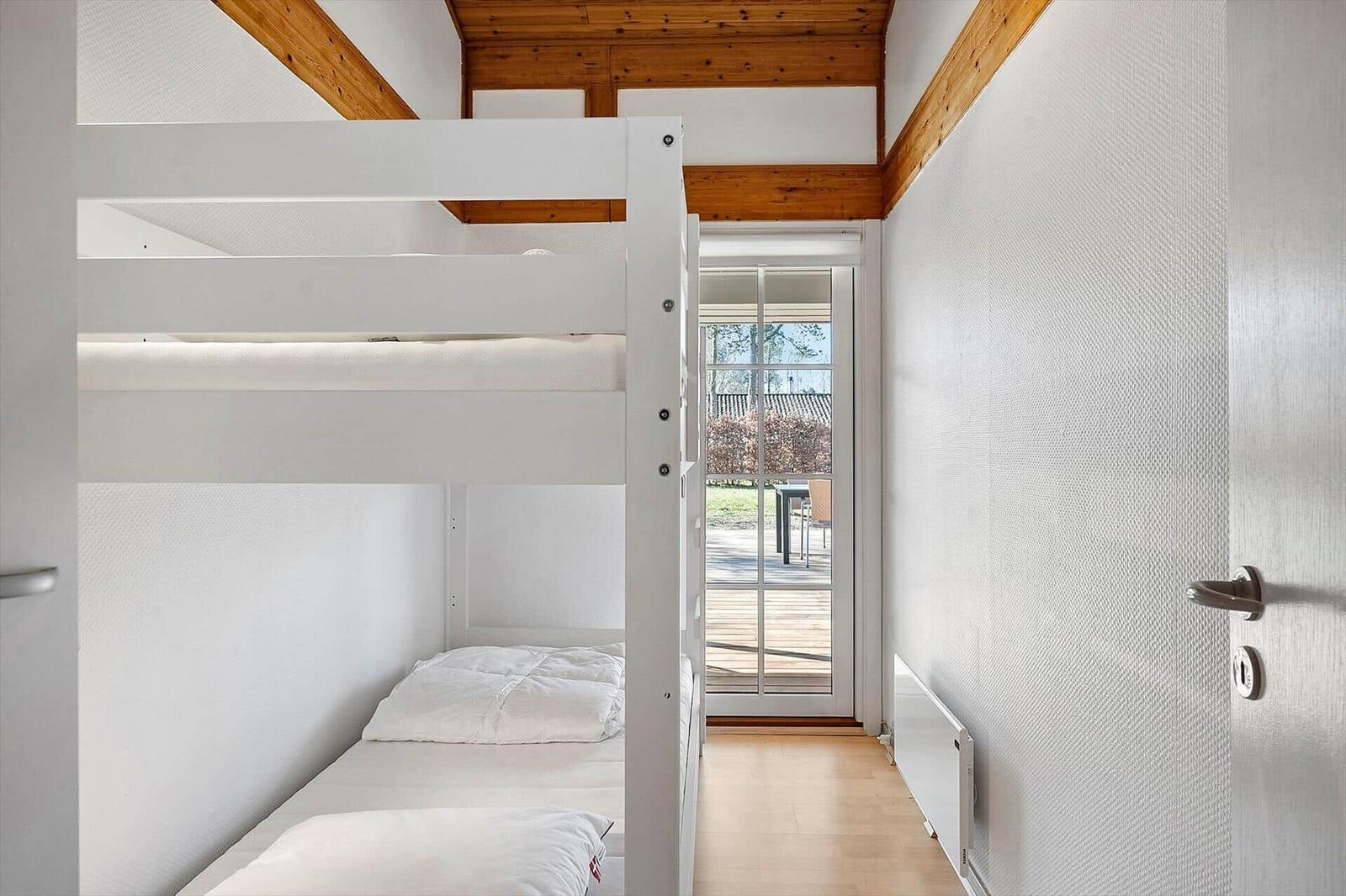 Zimmer mit Doppelstockbett, Holzdecke und Tür zum Balkon.