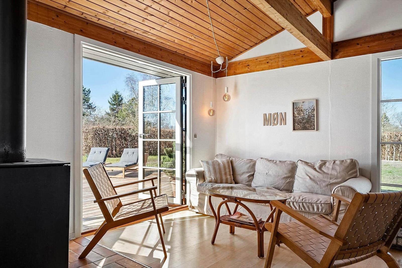Wohnbereich mit Sofa, zwei Stühlen und Blick auf die Terrasse.