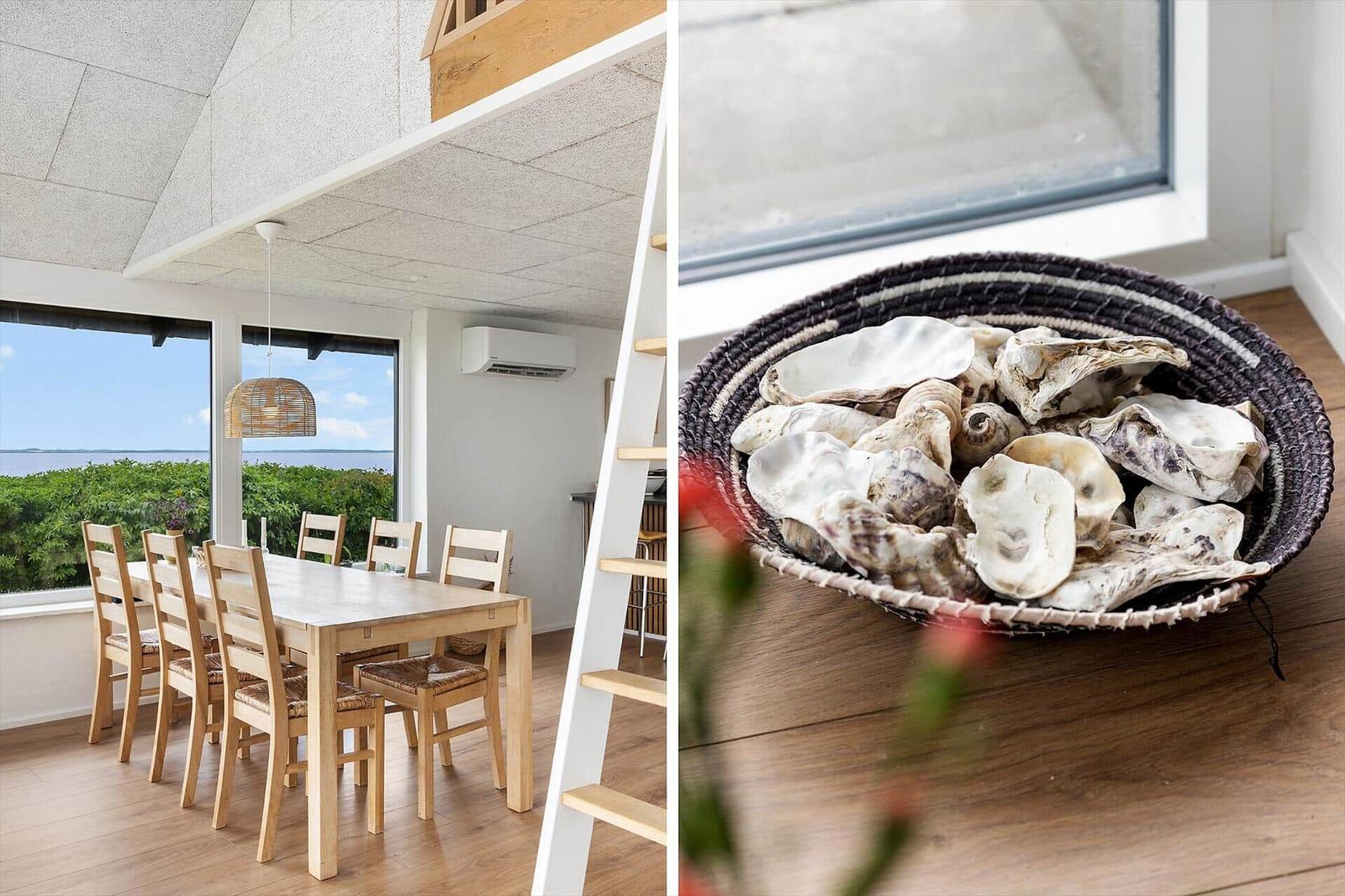 Dining room with table, chairs, and water view. Basket with shells by window.