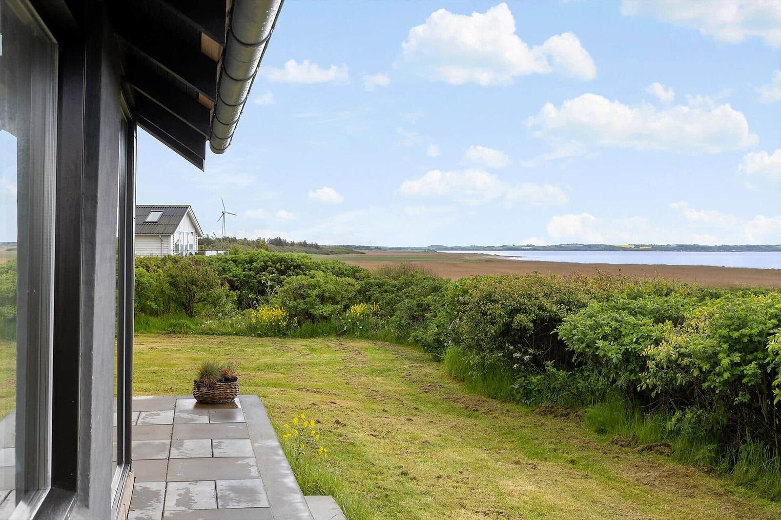 Terrace with view of green area and water. Wind turbine and house in background.