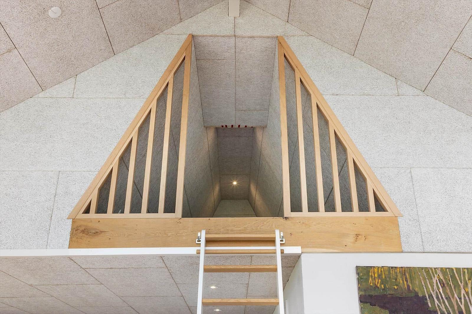 Wooden railing and ladder lead to a vaulted ceiling with stone walls.