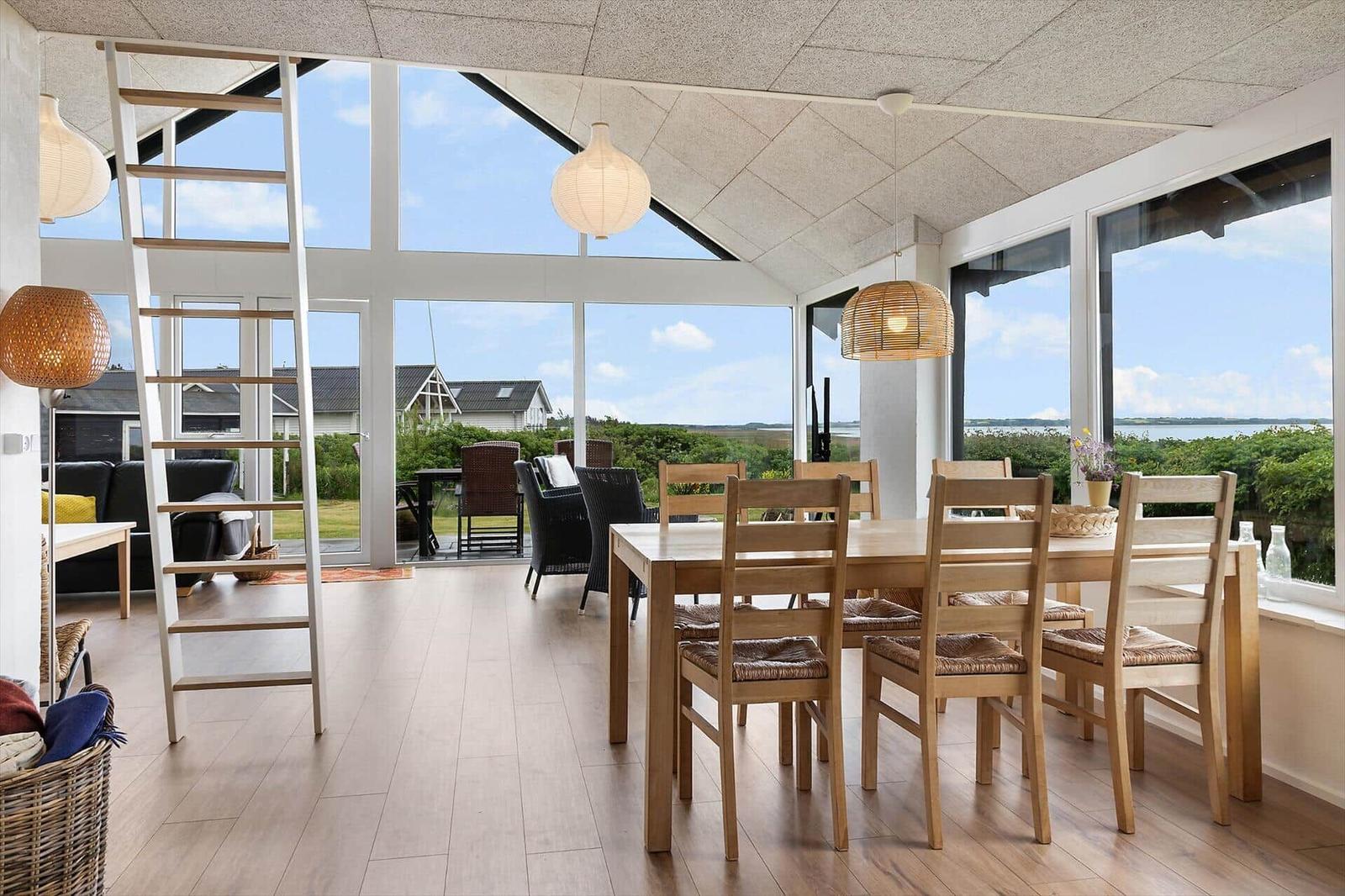 Dining room with wooden table and chairs, large windows, and view of the landscape.