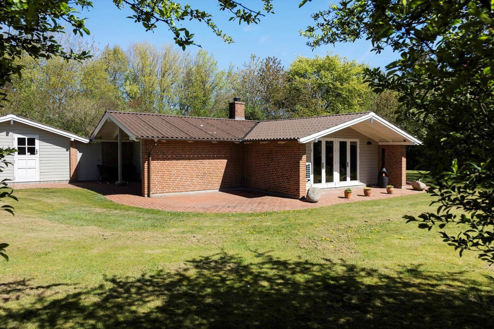 Einfamilienhaus mit Backsteinfassade und Terrasse im Grünen.