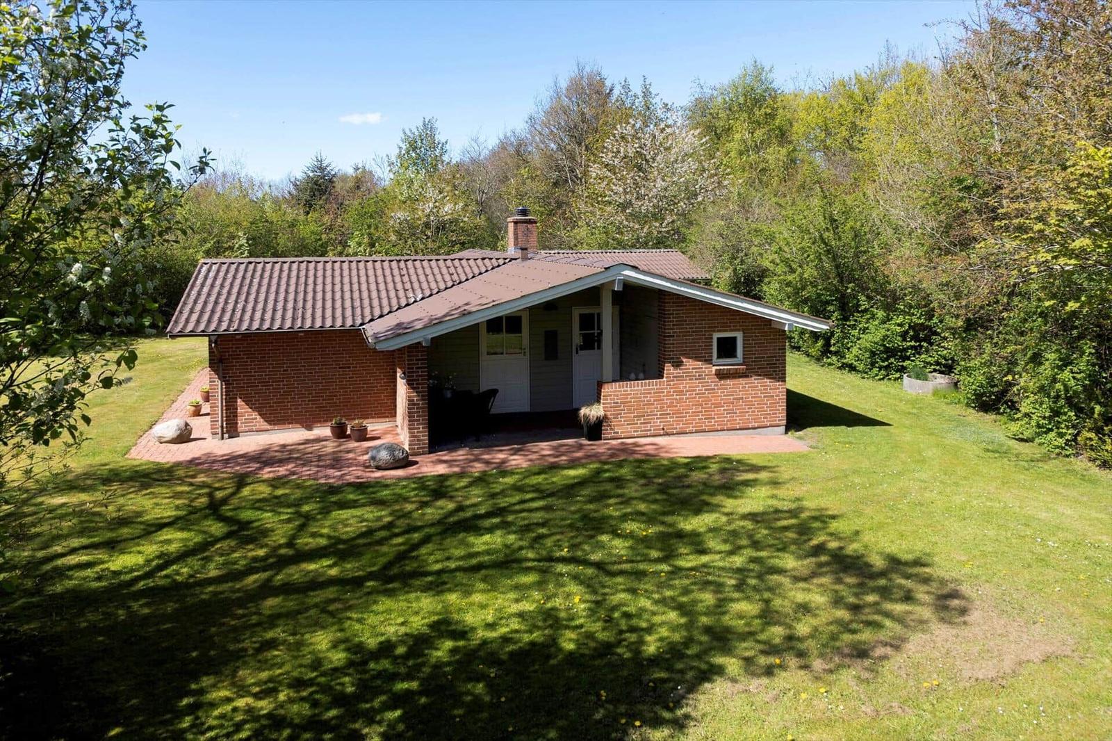 Ein kleines Haus mit Ziegelfassade und Terrasse im Grünen.