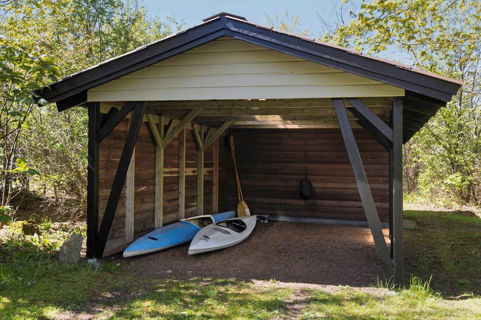 Schutzhaus mit zwei Kajaken und Paddeln im Wald