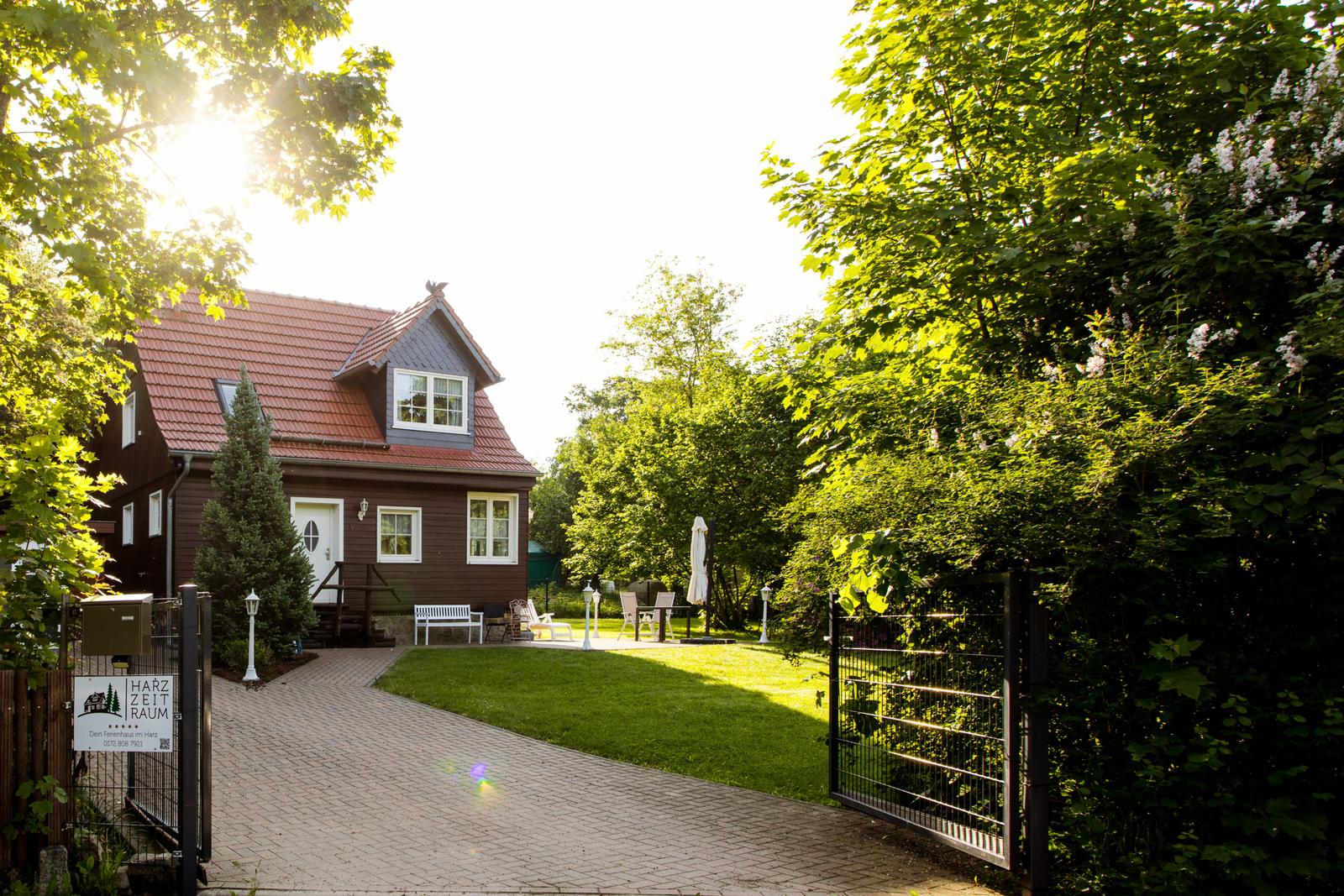 Ein Haus mit rotem Dach, weißer Tür und Gartenbereich mit Liege.