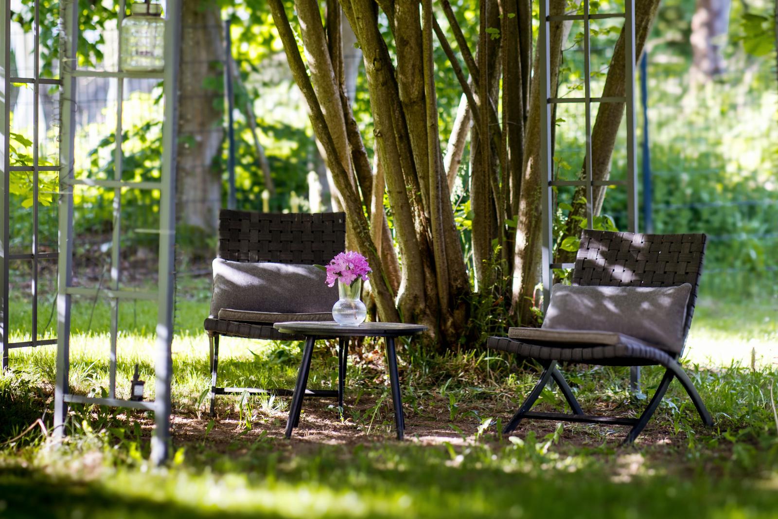 Zwei Stühle und ein Tisch unter Bäumen im Garten.