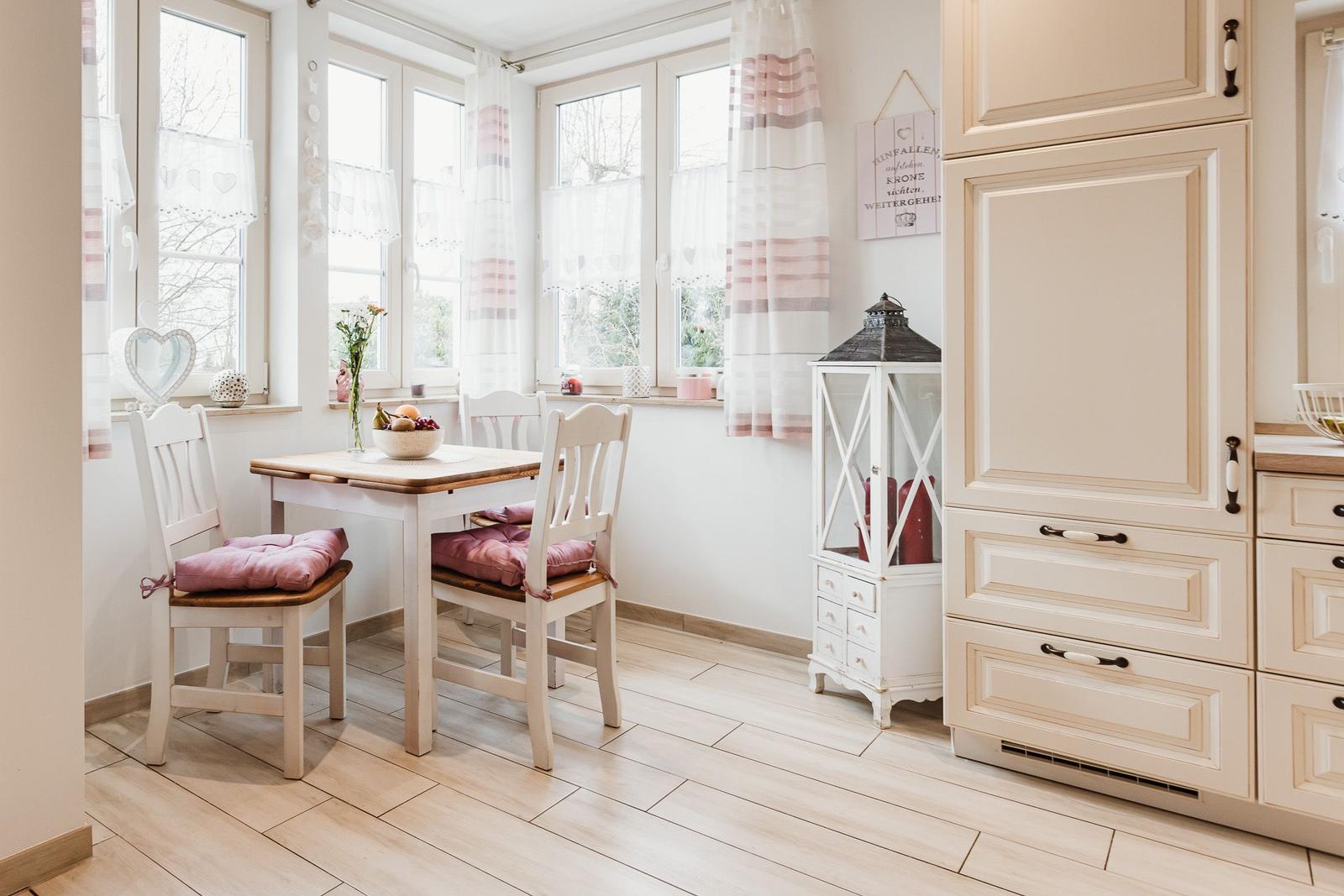 Essbereich mit Tisch, Stühlen und Küchenmöbeln an Fensterfront