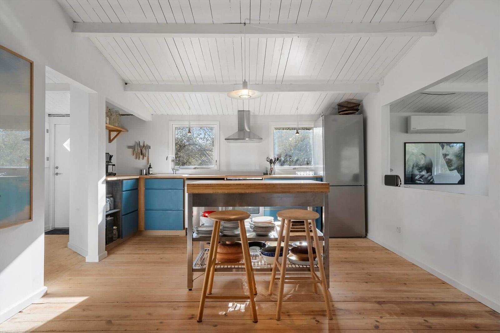 Kitchen with wooden floor, blue cabinets, and kitchen island with stools.