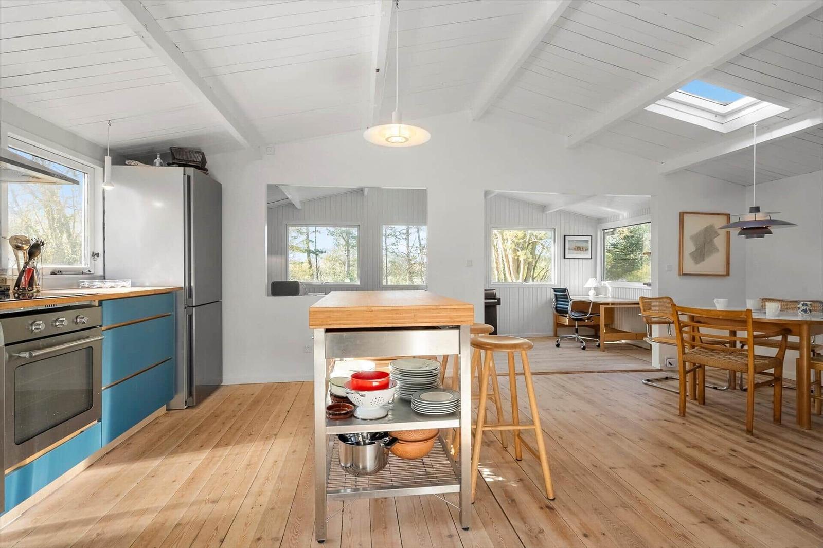 Kitchen with dining area and workspace. Wooden floor, white walls and ceiling beams.