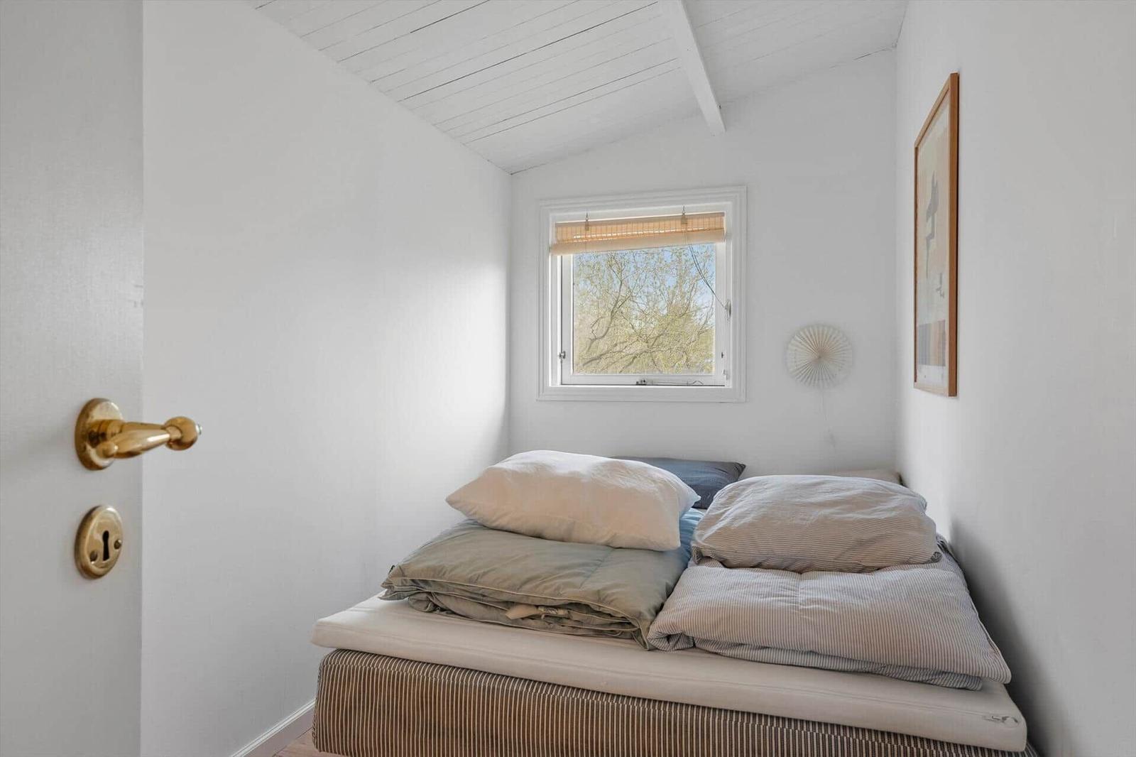 Bedroom with bed, window, and wall art. Ceiling with wood paneling.