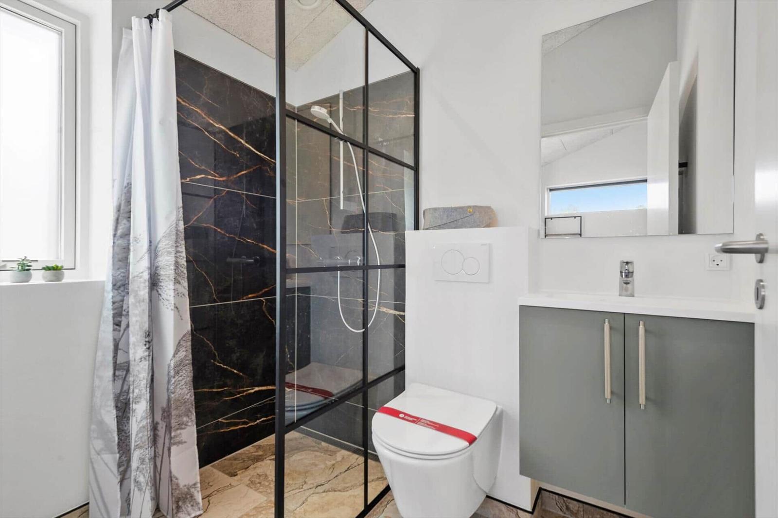 Badezimmer mit Dusche, Toilette und Waschbecken.