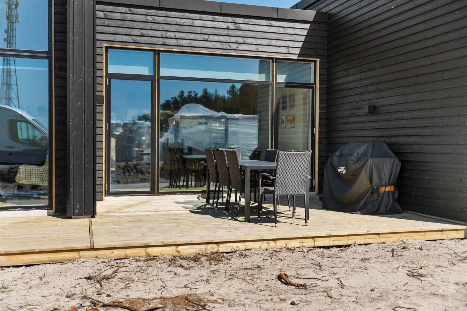 Terrasse mit Tisch und Stühlen vor modernem Haus mit Glasfront