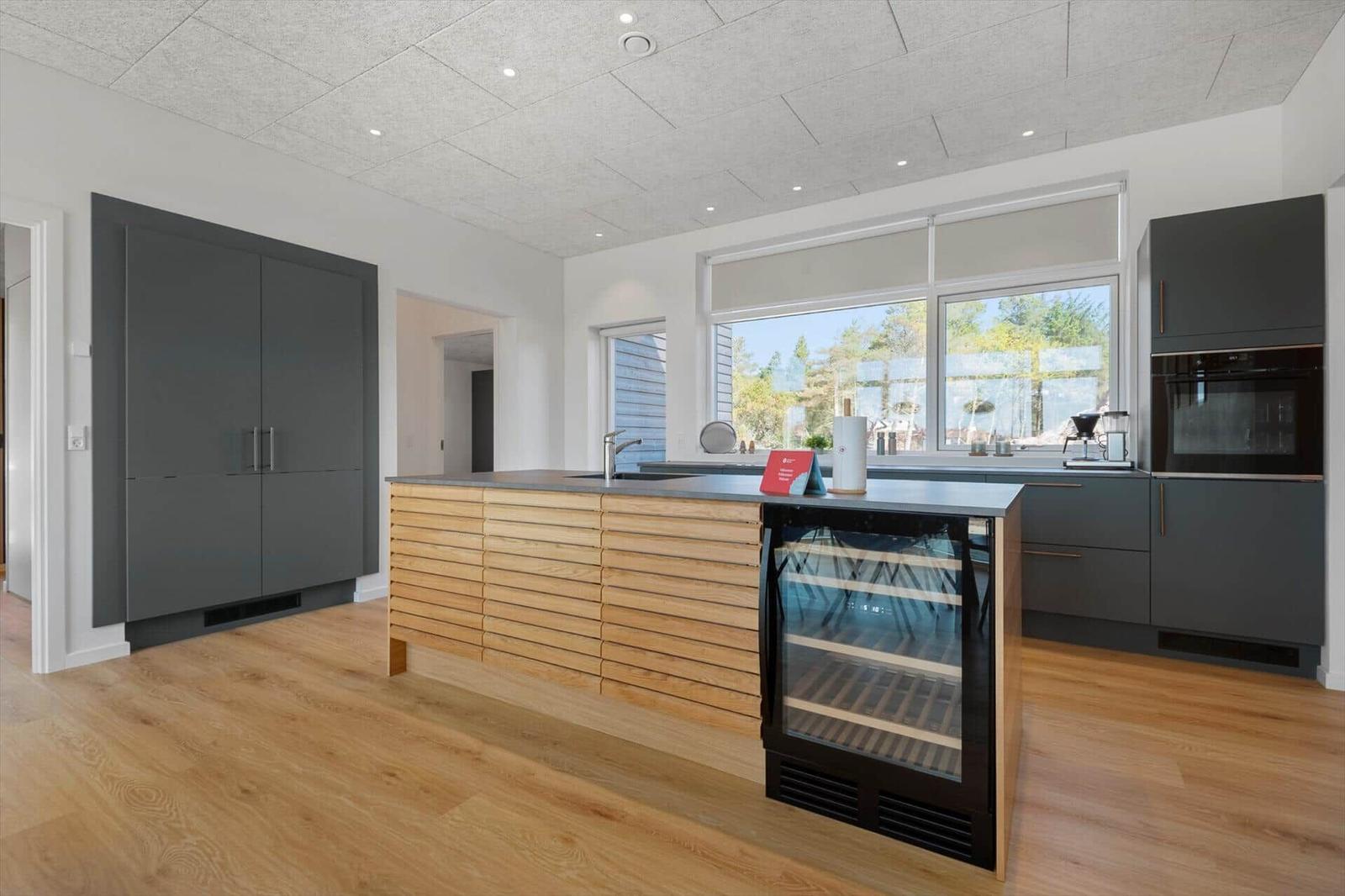 Moderne Küche mit Holzinsel, integriertem Kühlschrank und großen Fenstern.
