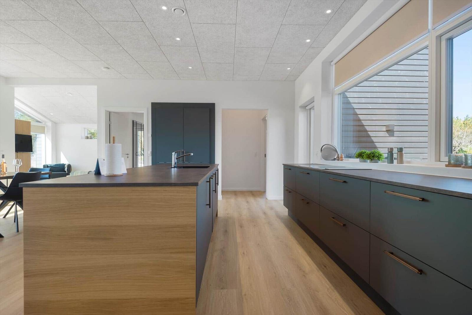 Moderne Küche mit Holzfußboden und dunklen Schränken. Große Fenster und Kücheninsel.