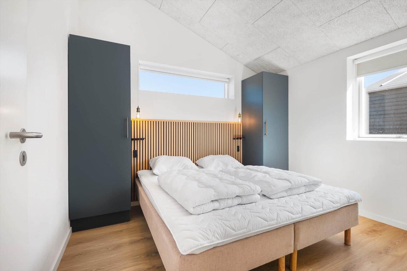 Schlafzimmer mit Bett, zwei Schränken und Fenstern