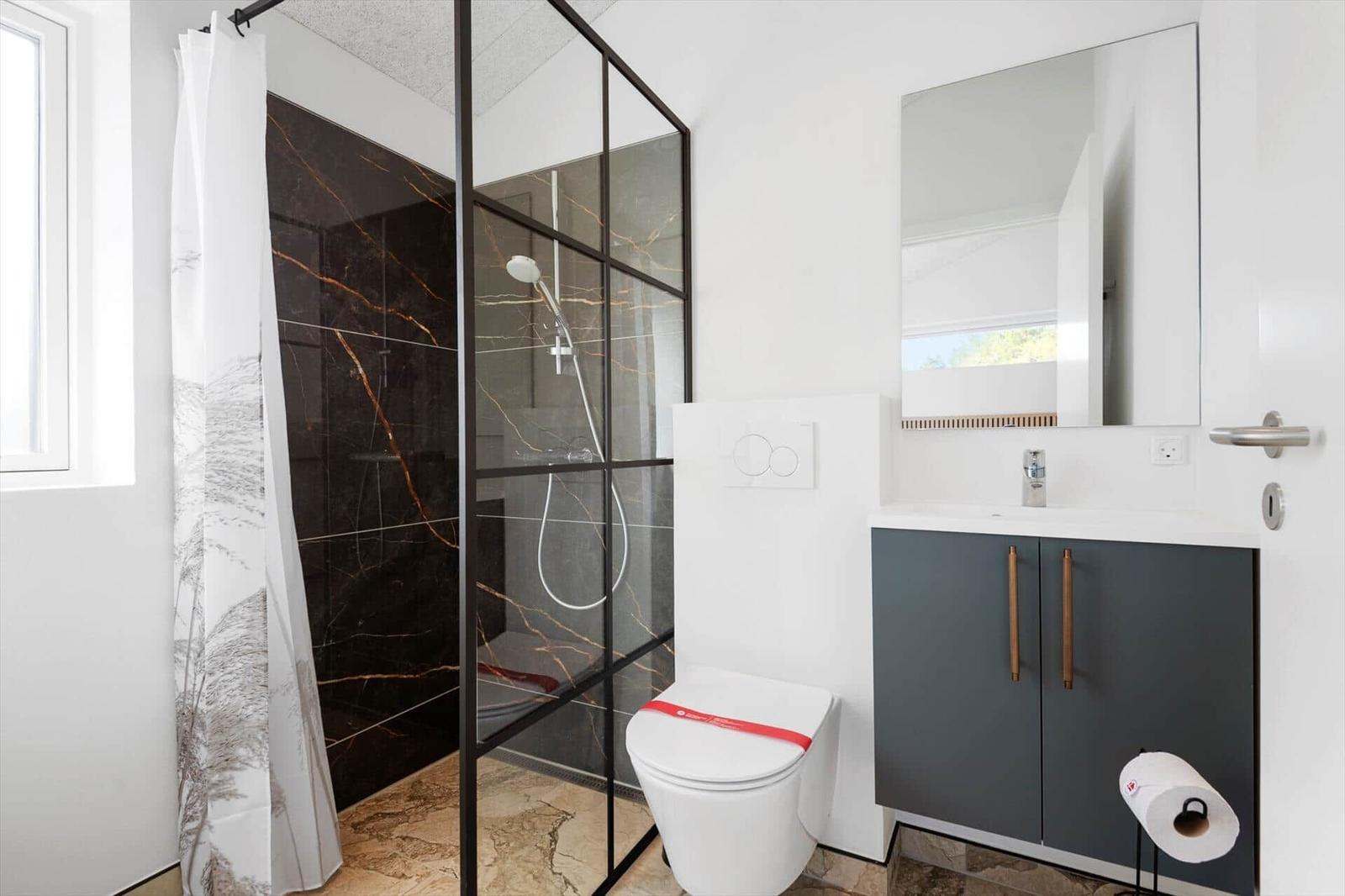 Badezimmer mit Dusche, Toilette und Waschbecken.