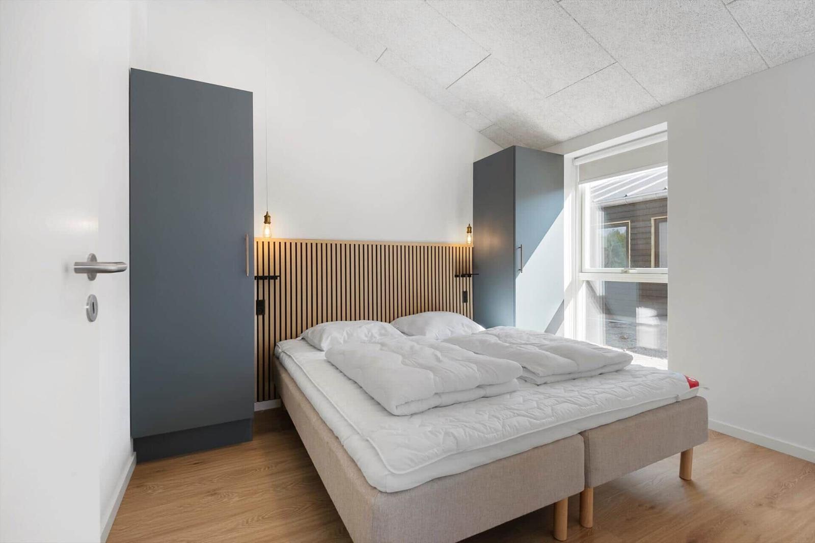 Schlafzimmer mit Bett, Holzdecke und Fenster. Zwei Schränke an den Wänden.