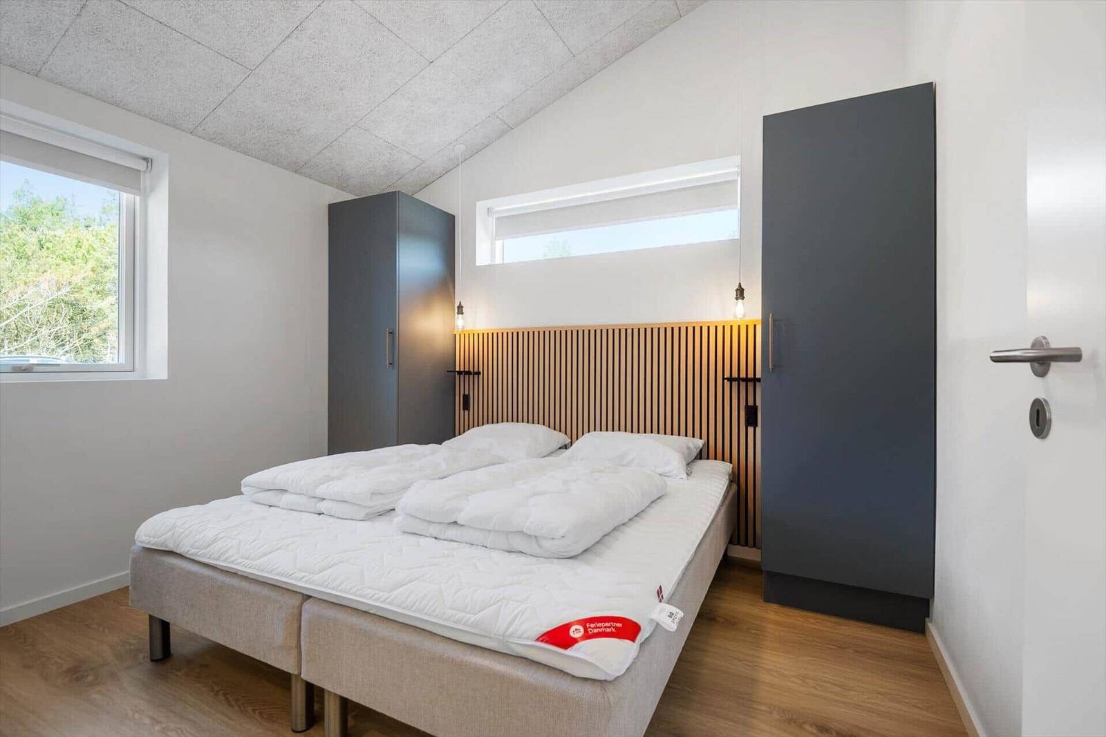 Schlafzimmer mit Doppelbett, Holzoberseite, zwei Schränken und Fenster.