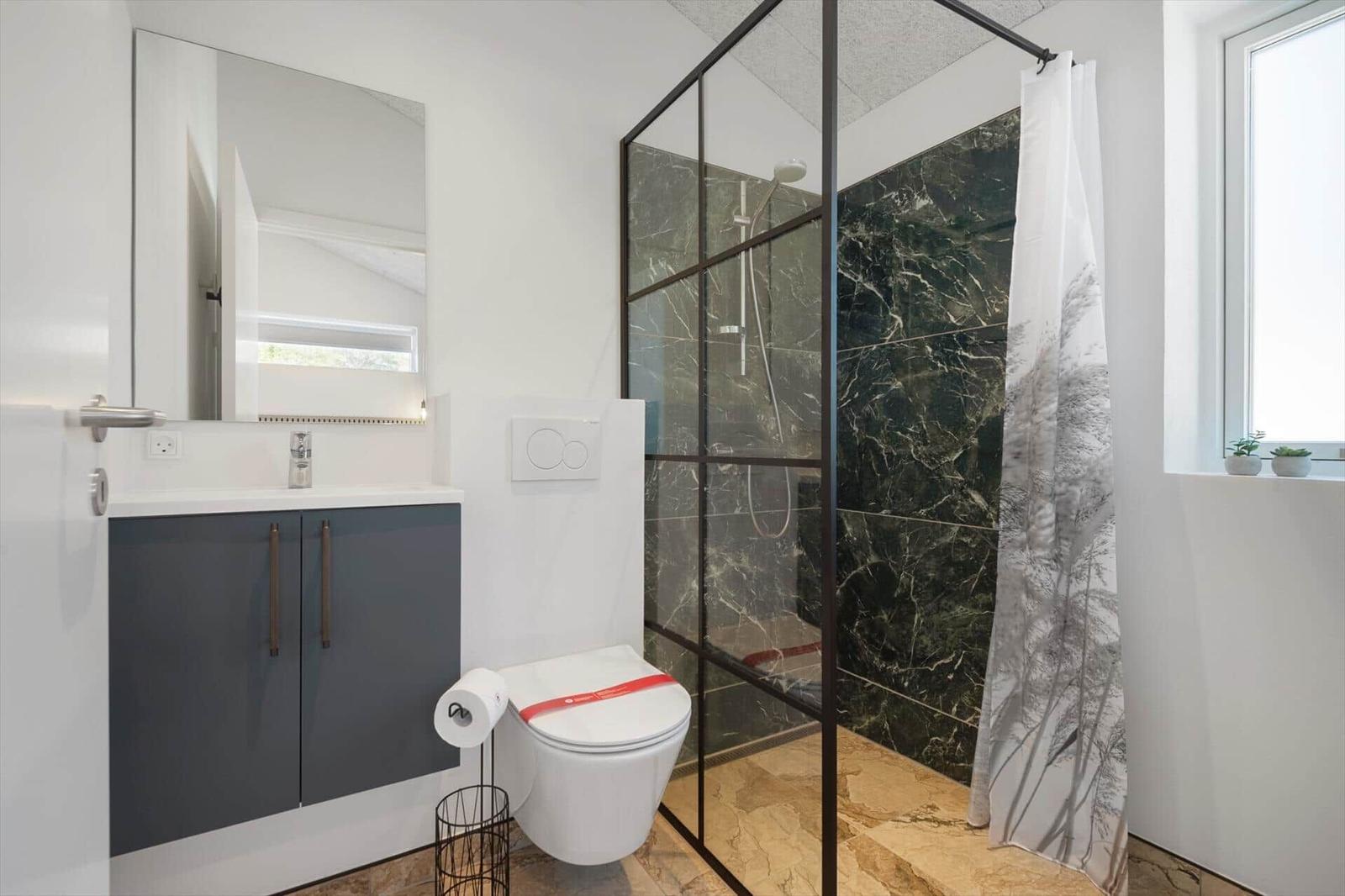 Badezimmer mit Dusche, Toilette und Waschbecken.