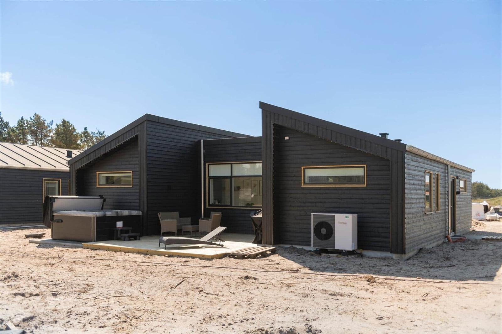Moderne Ferienhaus mit Außenterrasse, Whirlpool und Sitzgelegenheiten.