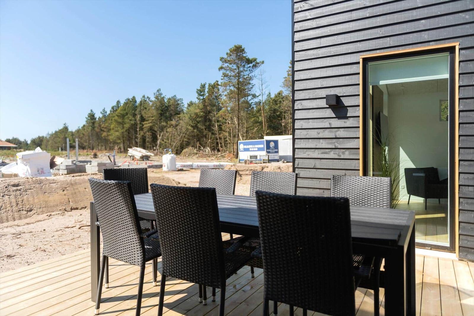 Terrasse mit Tisch und Stühlen neben einem Haus mit Glasfront.