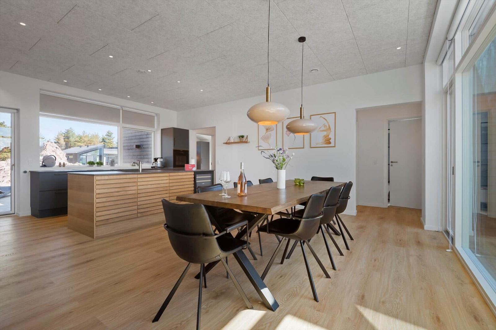 Essbereich mit Holztisch und Stühlen, Küche mit Holzfronten und großem Fenster.