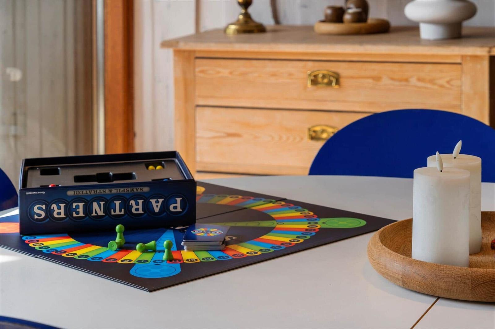 Tisch mit Brettspiel, Kerzen und Schrank im Hintergrund