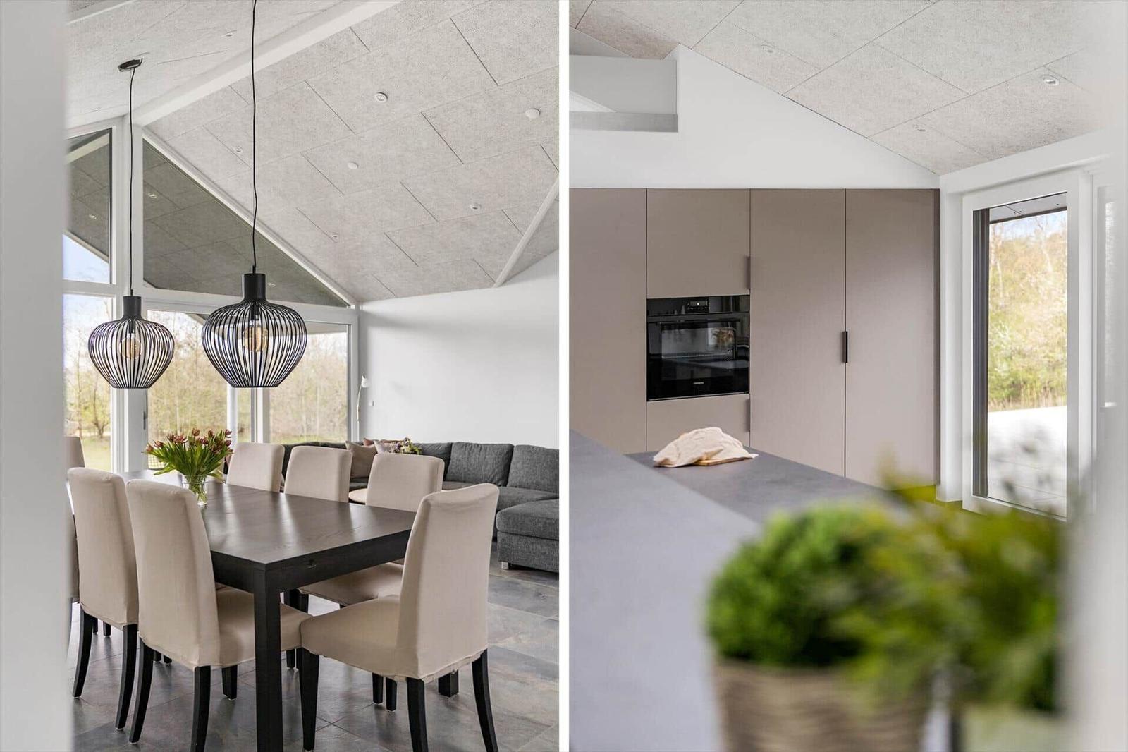 Essbereich mit Tisch und Stühlen unter hohem Dach. Küche mit integriertem Backofen und Fenster.