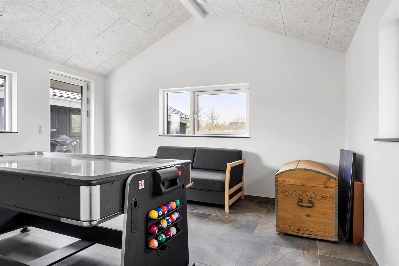 Raum mit Billardtisch, Sofa und Holzschatulle. Fenster und Tür zur Außenseite.