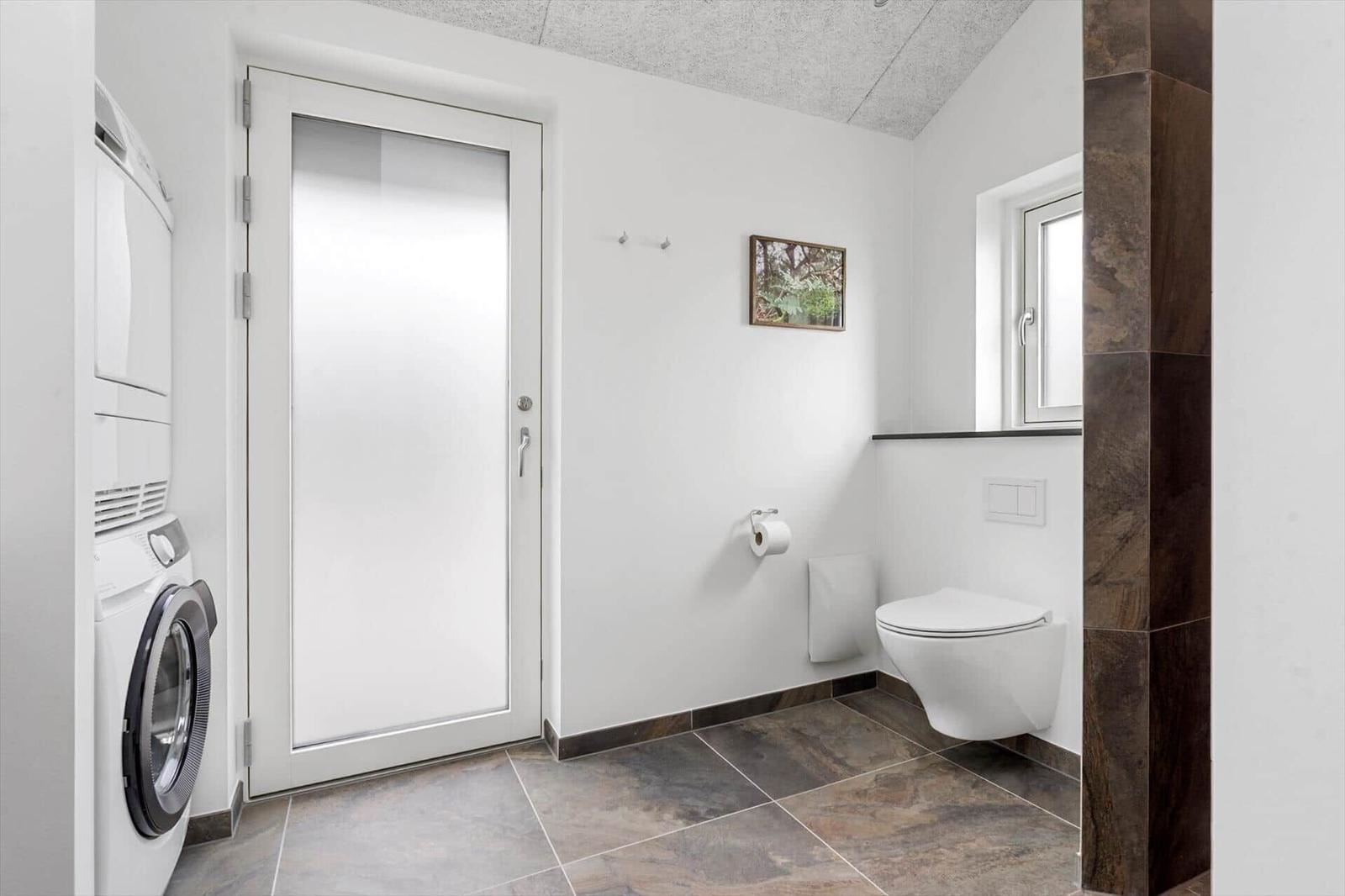 Badezimmer mit Toilette, Waschmaschine und Fenster
