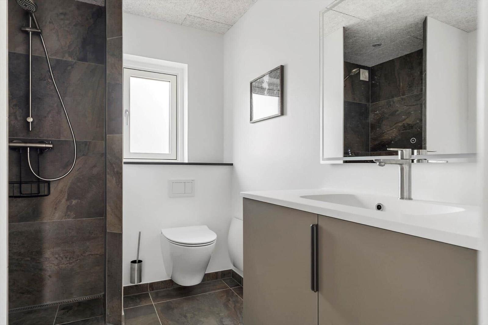 Badezimmer mit Dusche, Toilette und Waschbecken mit Spiegel.